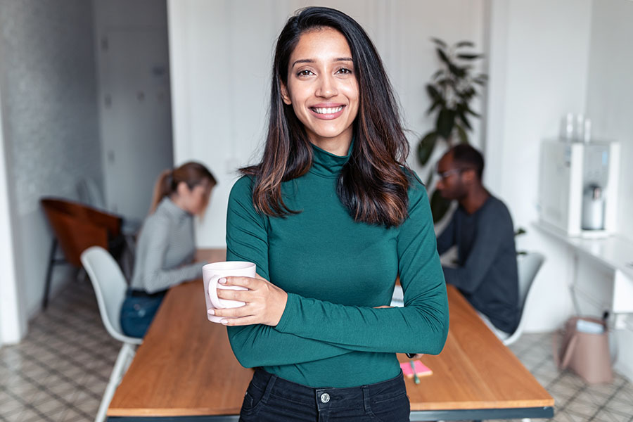 Business Owners Insurance - Portrait of Young Business Woman Standing in the Office with a Cup of Coffee
