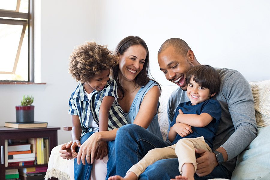 Personal Insurance - Family Having Fun and Smiling on Couch in Living Room with Open Window